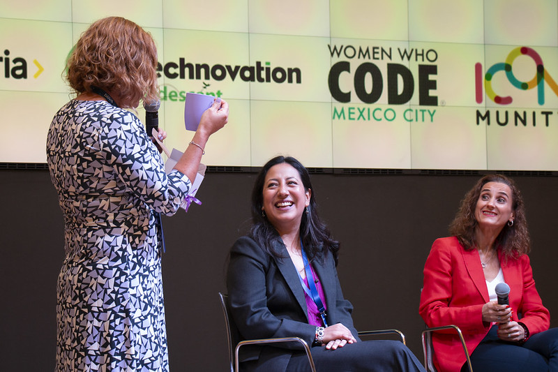 Panel de mujeres conversando en el escenario de Dev Day 4 Women
